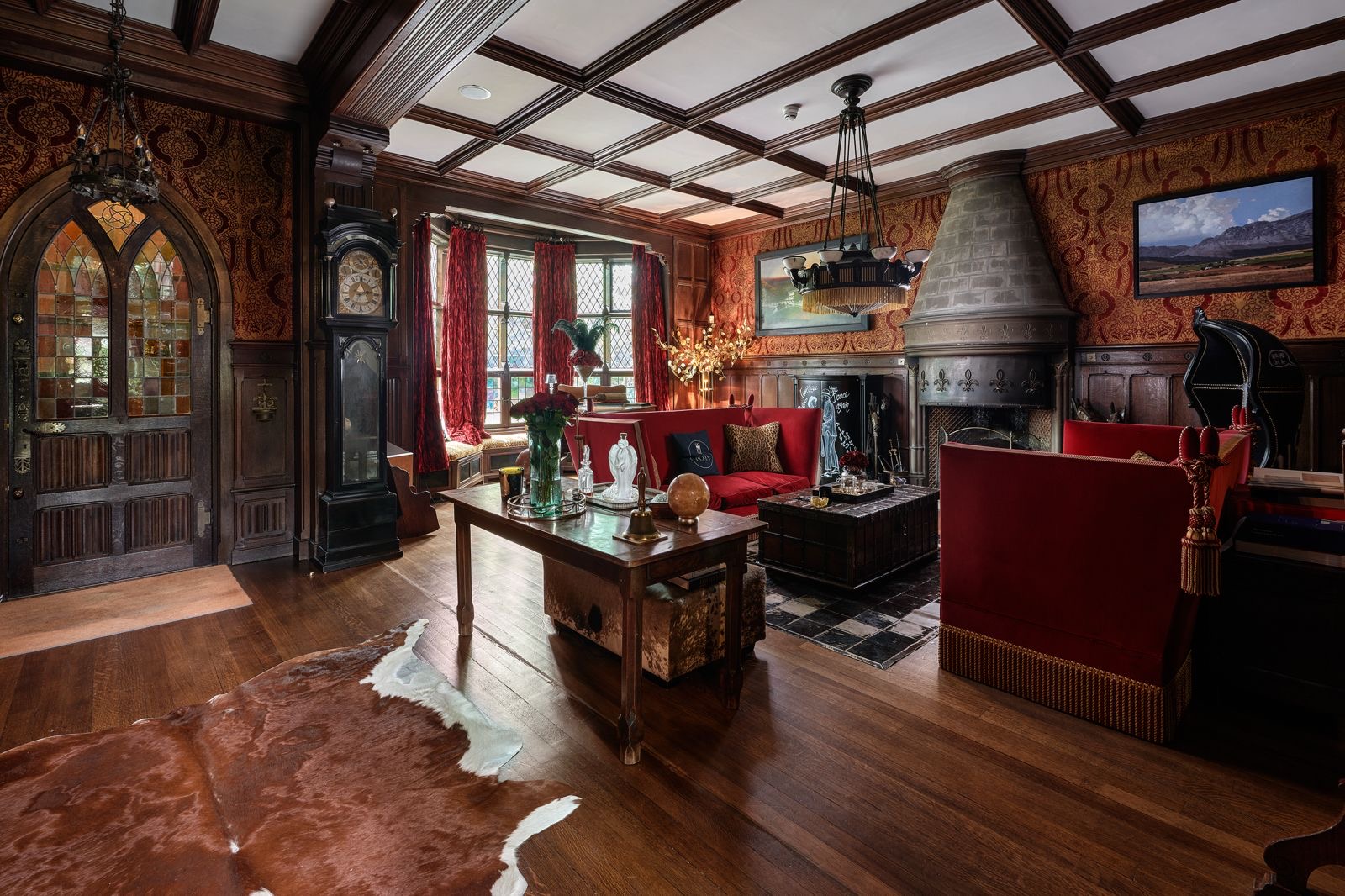 The great hall with a beamed ceiling, carved panelling and red sofas