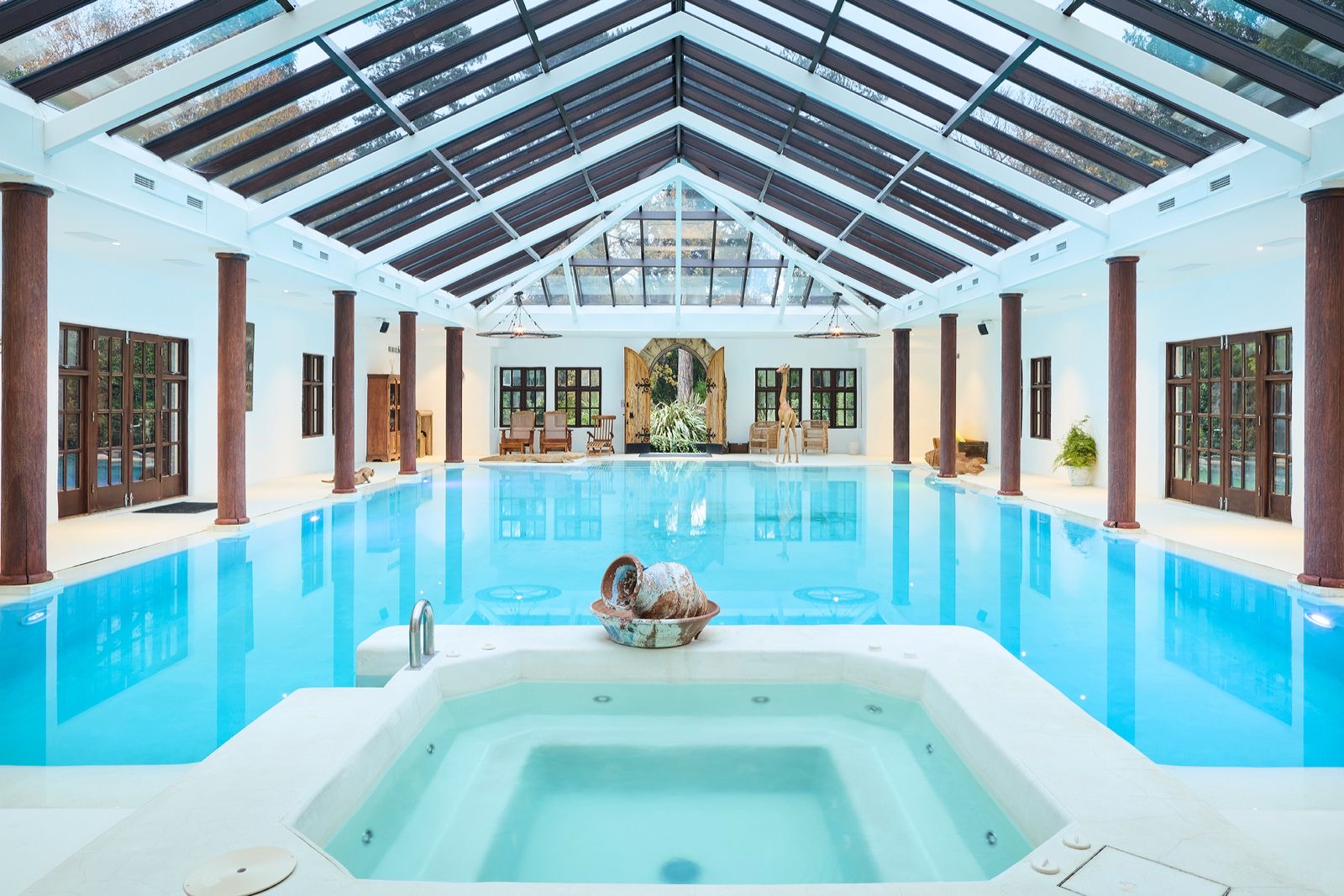 The hot tub at the end of the indoor swimming pool, beneath a pitched glass roof