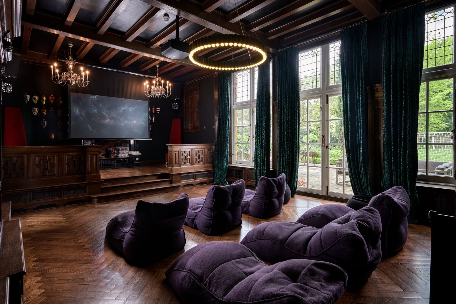 A panelled room with a low stage, a screen and floor cushions